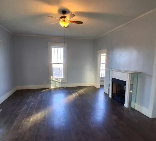 a view of empty room with a fireplace and wooden floor