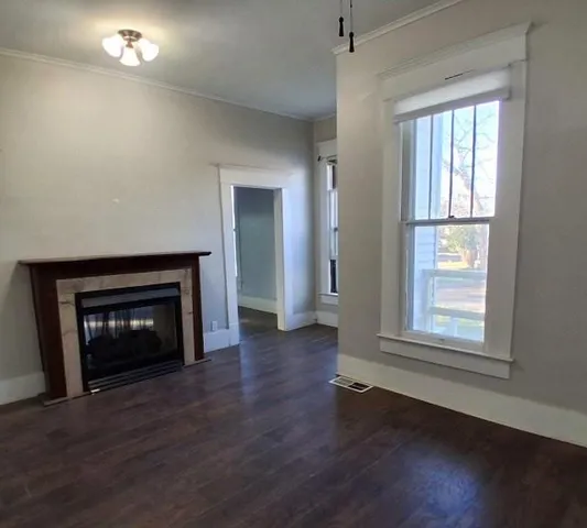 an empty room with wooden floor fireplace and windows