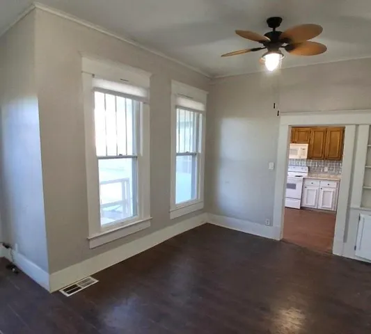 a view of an empty room with a window and wooden floor