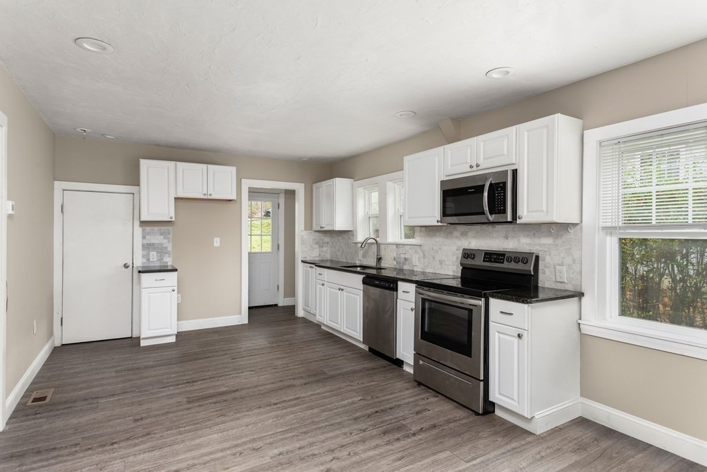 195 Eastern Avenue Worcester, MA 01605 - Photo 5 of 24 a kitchen with granite countertop a refrigerator a stove top oven a sink dishwasher and wooden floor