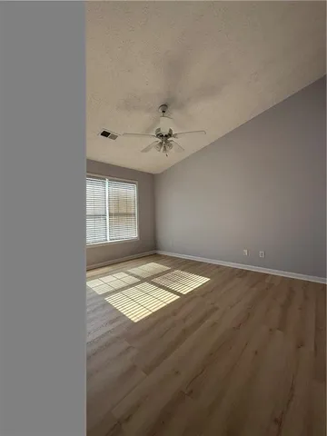 an empty room with a chandelier fan and windows