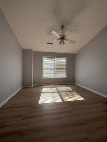 a view of an empty room with a window and wooden floor