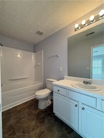 a bathroom with a granite countertop toilet a sink and a mirror