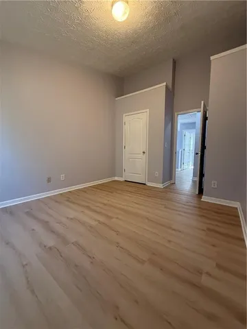 a view of an empty room with wooden floor and closet