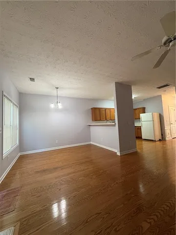 a view of an empty room with window and wooden floor