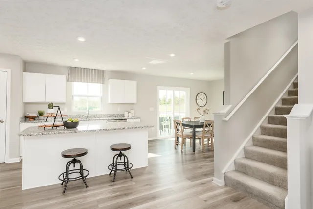 a kitchen with a dining table chairs and wooden floor