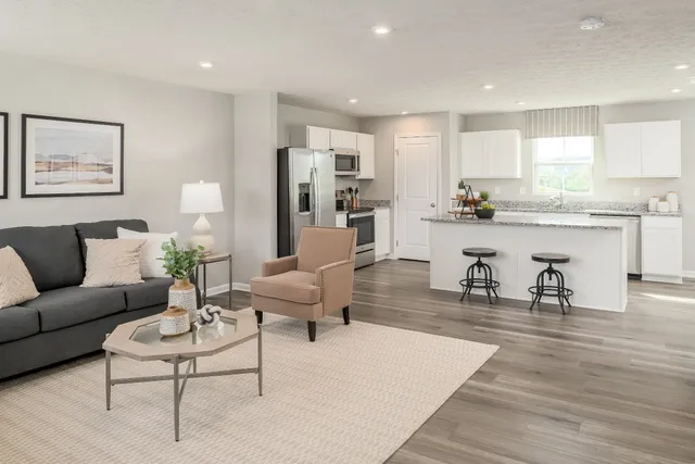 a living room with furniture kitchen view and a wooden floor
