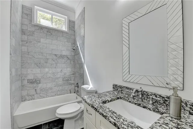 a bathroom with a granite countertop sink toilet and mirror