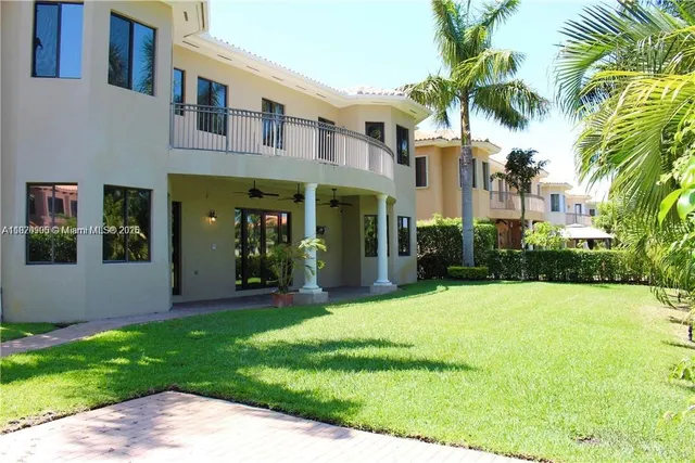 a view of a white house with a big yard and potted plants