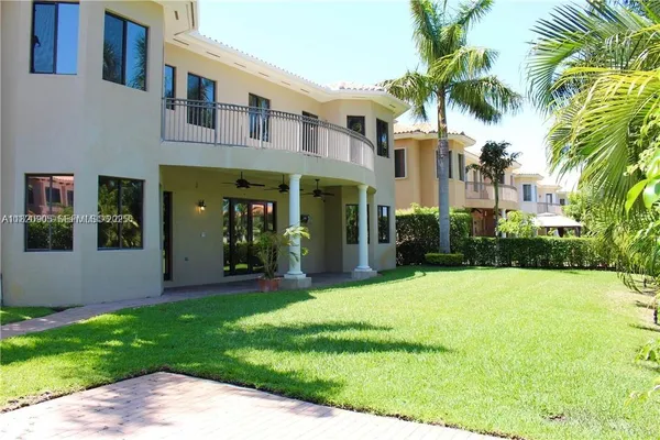 a view of a white house with a big yard and potted plants