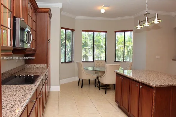 a kitchen with a stove a sink a kitchen island with chairs and wooden cabinets
