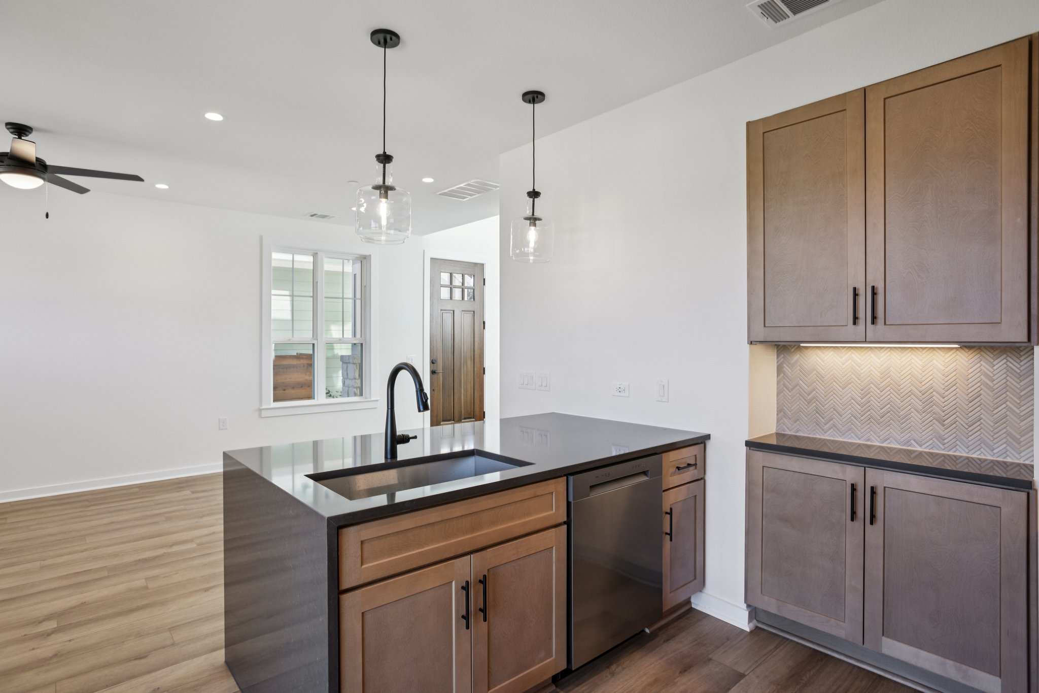 2414 Drew Lane, Unit 5 Austin, TX 78748 - Photo 11 of 24 Kitchen featuring a peninsula, dark wood finished floors, dark stone countertops, pendant lighting, and stainless steel dishwasher