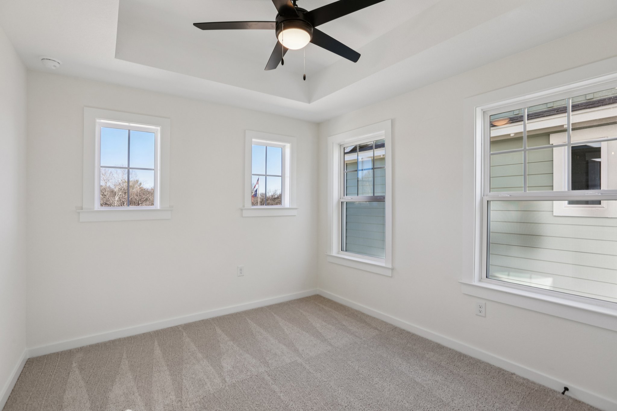 2414 Drew Lane, Unit 5 Austin, TX 78748 - Photo 13 of 24 Empty room featuring light carpet, a tray ceiling, and a ceiling fan