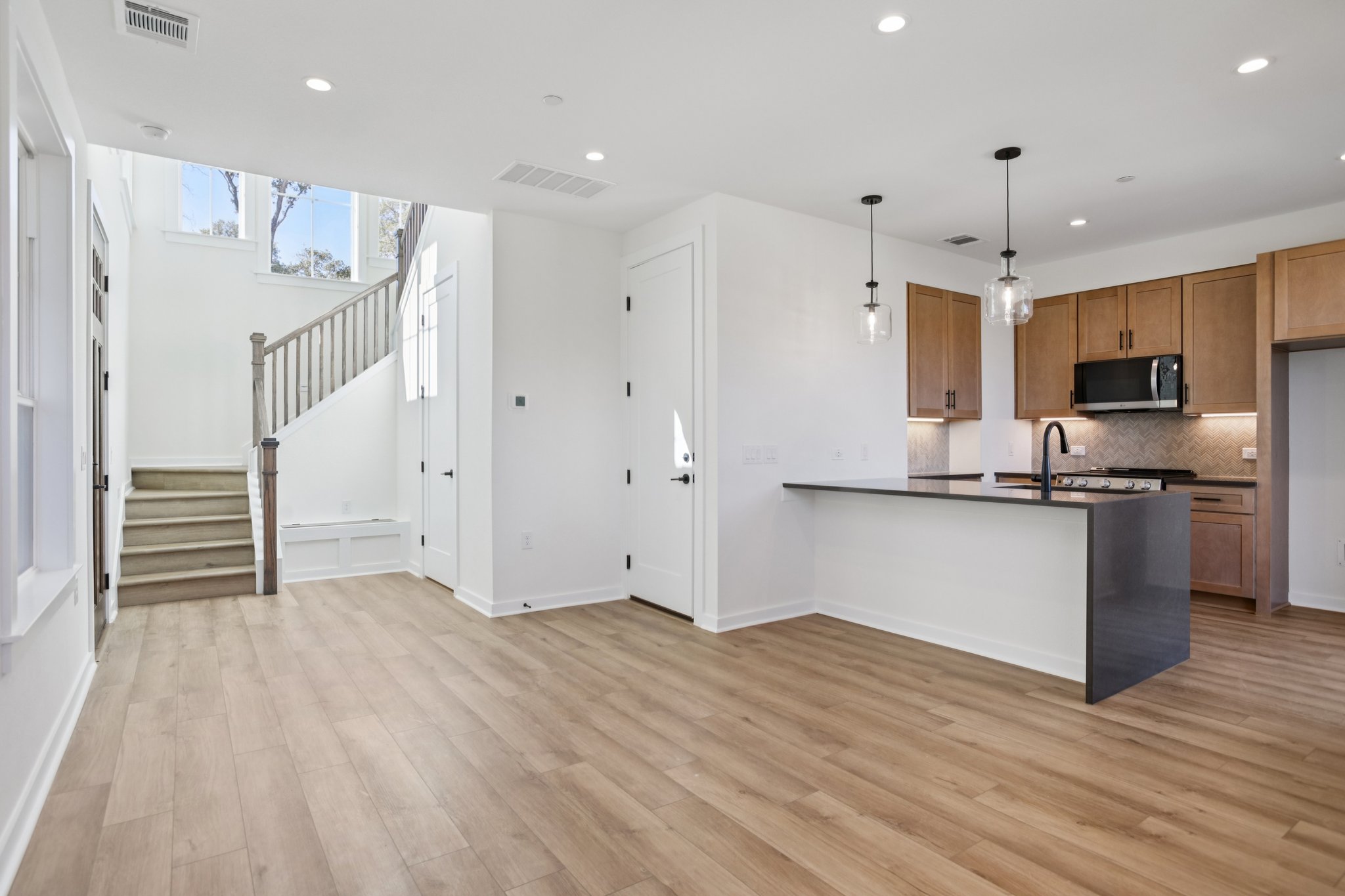2414 Drew Lane, Unit 5 Austin, TX 78748 - Photo 8 of 24 Kitchen featuring pendant lighting, a peninsula, brown cabinetry, stainless steel microwave, and recessed lighting