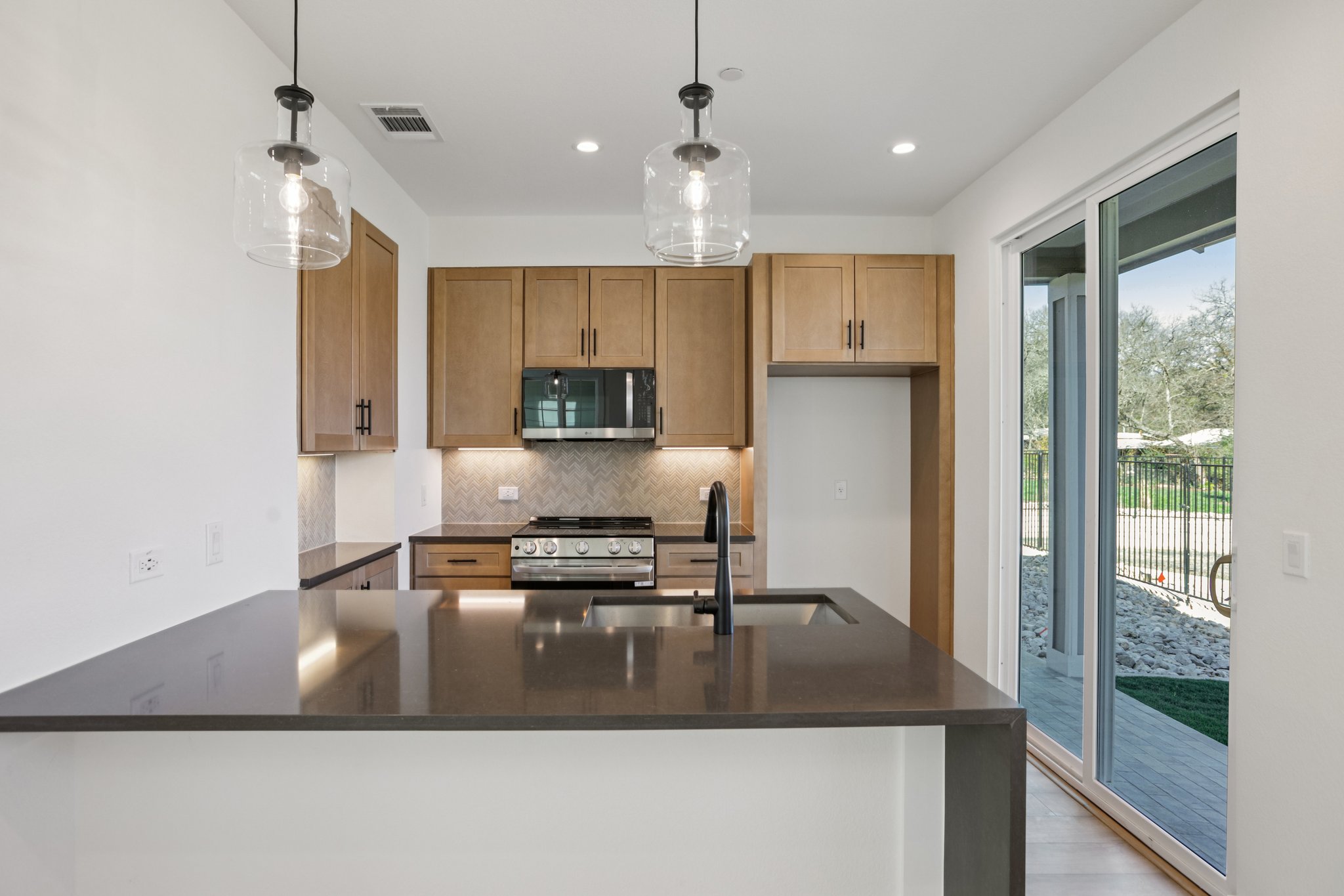2414 Drew Lane, Unit 5 Austin, TX 78748 - Photo 9 of 24 Kitchen with dark stone counters, a peninsula, decorative light fixtures, stainless steel appliances, and backsplash