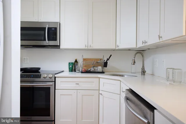 a kitchen with granite countertop white cabinets and stainless steel appliances