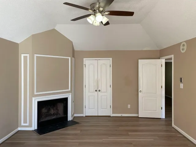a view of a livingroom with a fireplace a ceiling fan and wooden floor