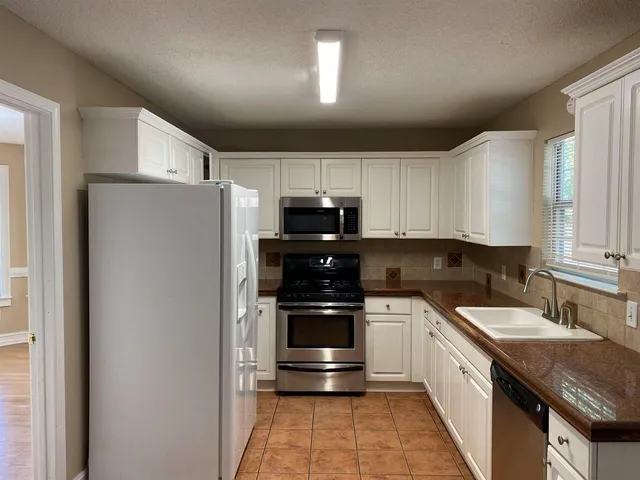 a kitchen with stainless steel appliances granite countertop a refrigerator and a stove