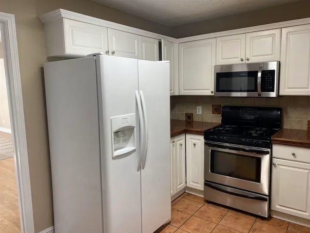 a white refrigerator freezer and a stove sitting inside of a kitchen