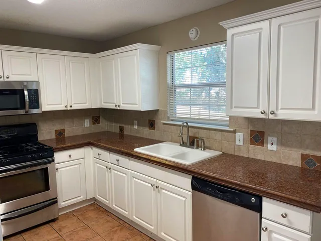 a kitchen with granite countertop white cabinets and white appliances