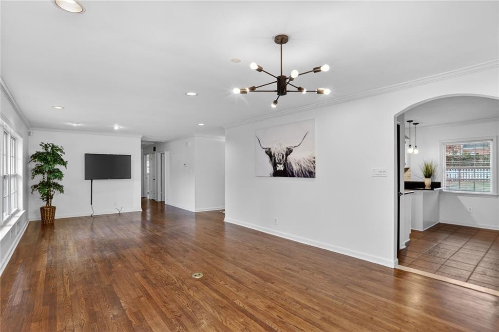 1127 Moores Mill Road Northwest Atlanta, GA 30327 - Photo 7 of 20 a view of a big room with wooden floor a chandelier fan and windows