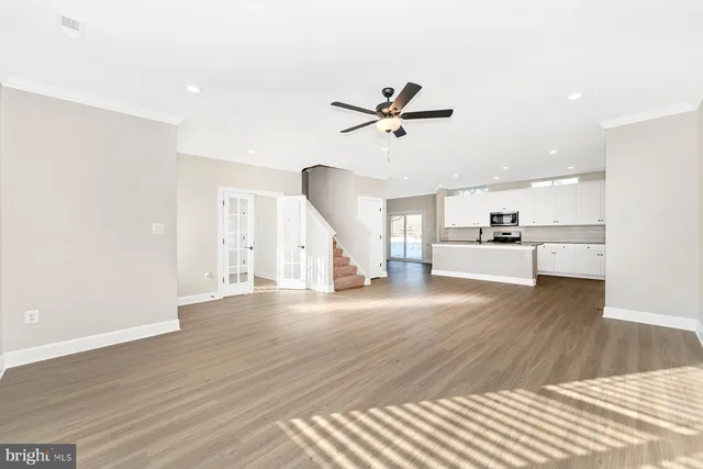 a view of a room with wooden floor ceiling fan and window