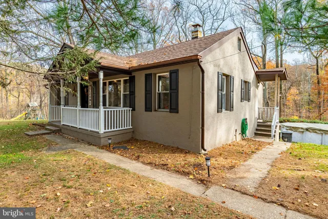 a view of a house with a small yard and large tree