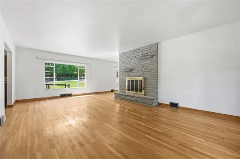 a view of empty room with wooden floor and fireplace