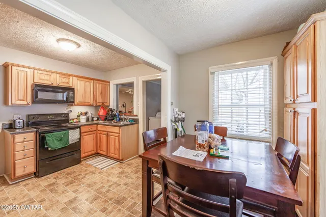 a kitchen with a stove a sink dishwasher a dining table and chairs with wooden floor