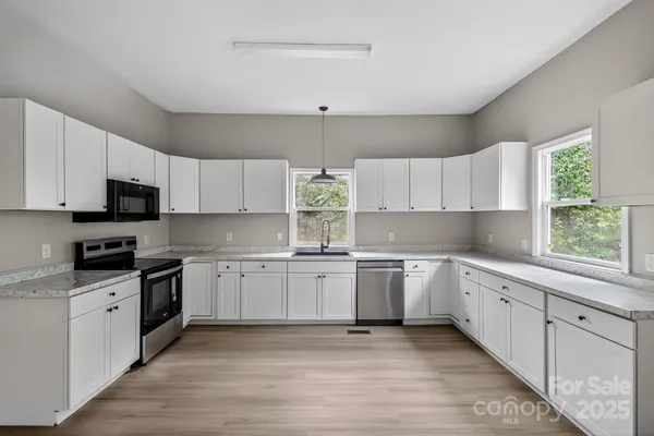 a kitchen with granite countertop white cabinets white appliances a sink and a window