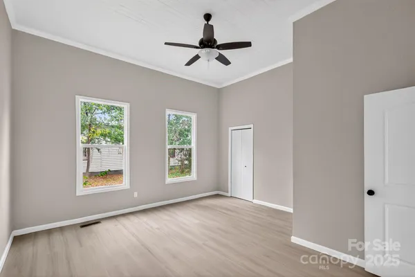 a view of an empty room with a window and wooden floor