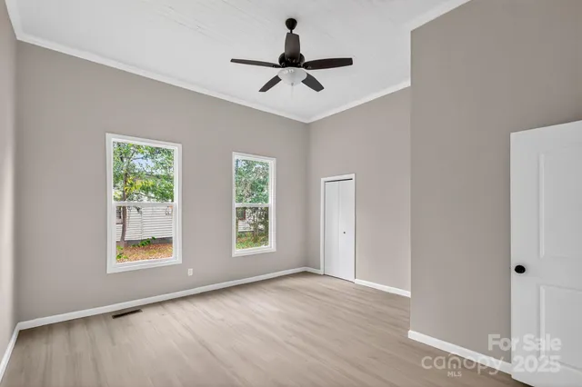 a view of an empty room with a window and wooden floor