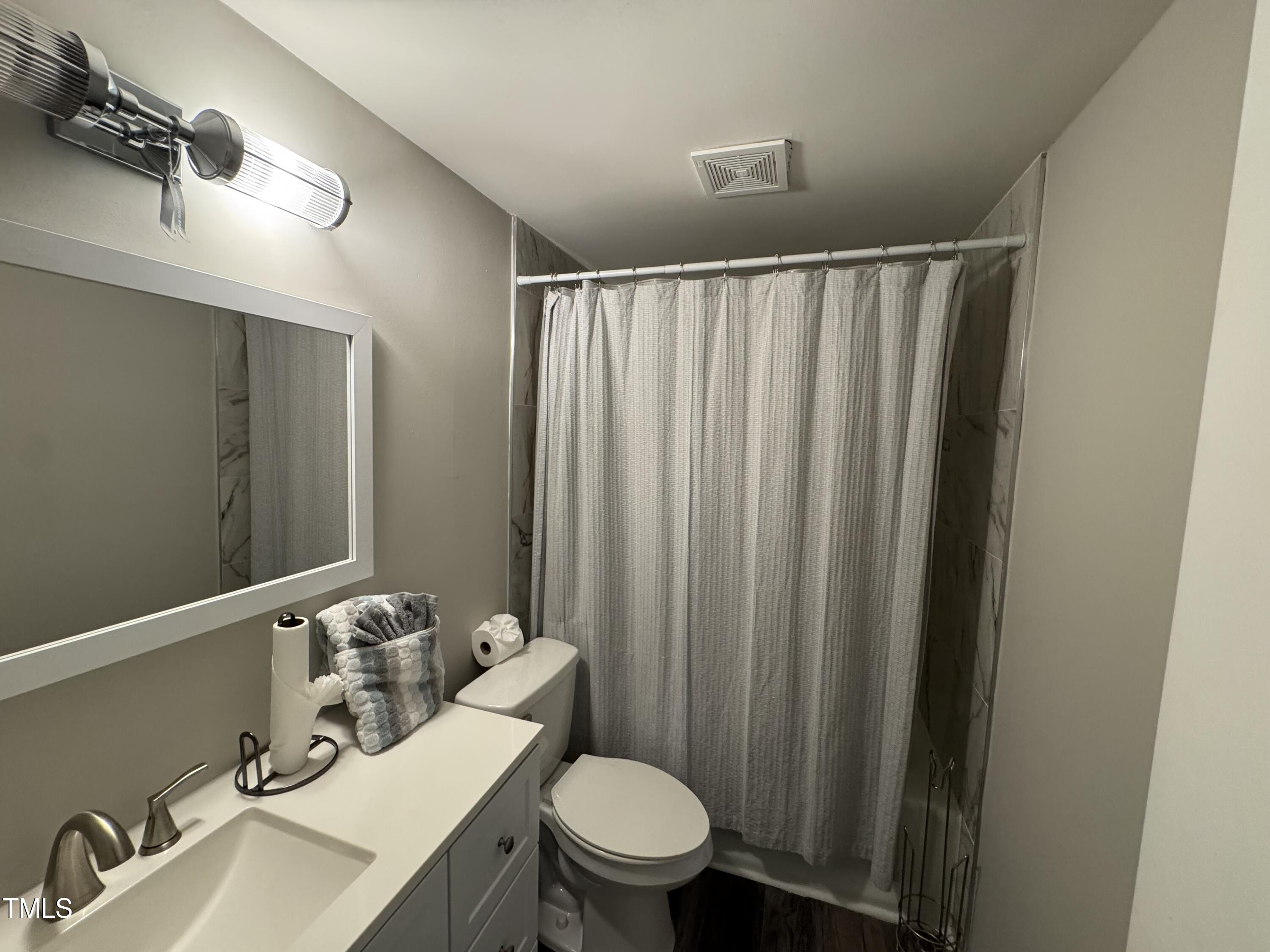 1513 Shelley Road Raleigh, NC 27612 - Photo 22 of 24 a bathroom with a sink a toilet a mirror and shower curtain