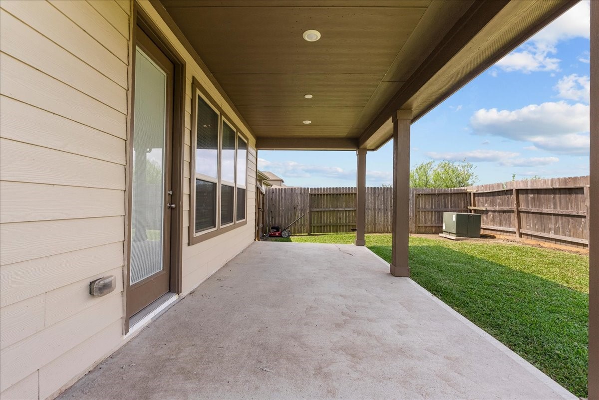 2320 Rosemary Street Rosenberg, TX 77469 - Photo 9 of 40 This photo showcases a covered patio with a concrete floor, adjacent to a fenced backyard with grassy lawn, ideal for outdoor relaxation and entertaining.