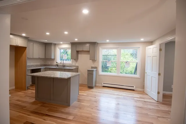 a large kitchen with stainless steel appliances granite countertop a stove a refrigerator a sink and a microwave oven on the wooden floor