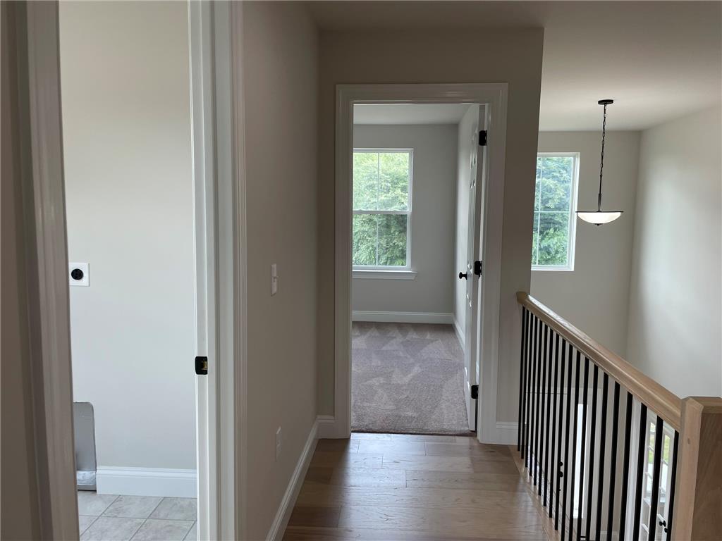 5043 Chapmans Road Orefield, PA 18069 - Photo 28 of 30 A well-lit upstairs hallway features hardwood flooring and a stylish black iron railing.