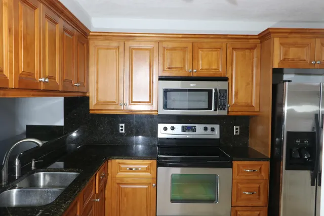 a kitchen with granite countertop a stove a sink and a microwave