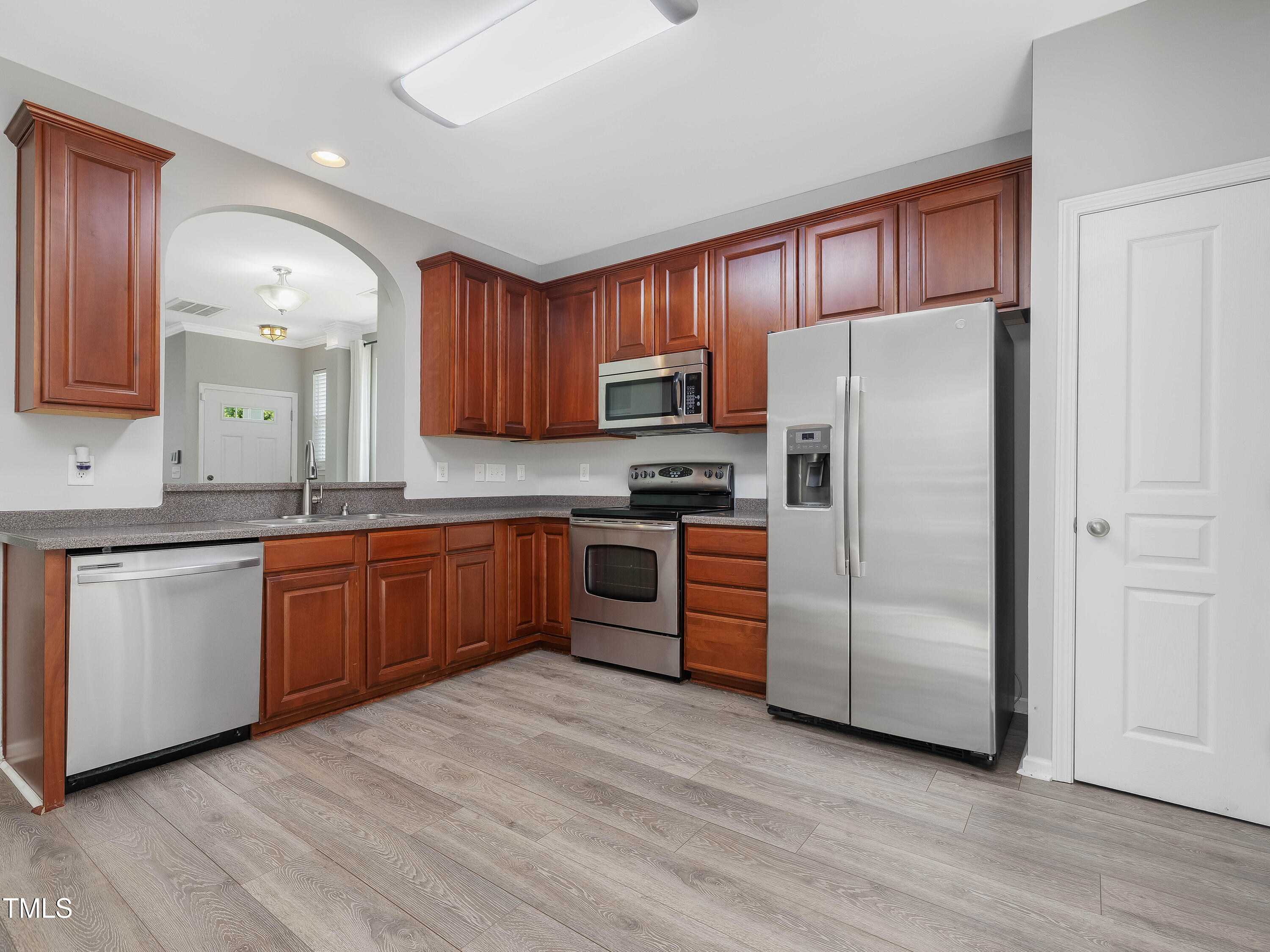 7661 Winners Edge Street Raleigh, NC 27617 - Photo 4 of 13 a kitchen with granite countertop wooden floors stainless steel appliances and white cabinets