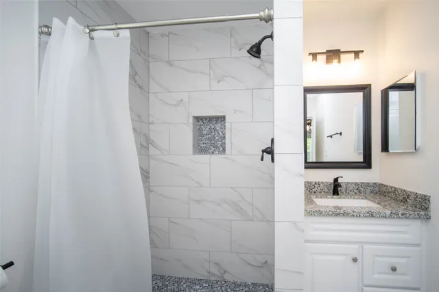 a bathroom with a granite countertop shower sink and mirror