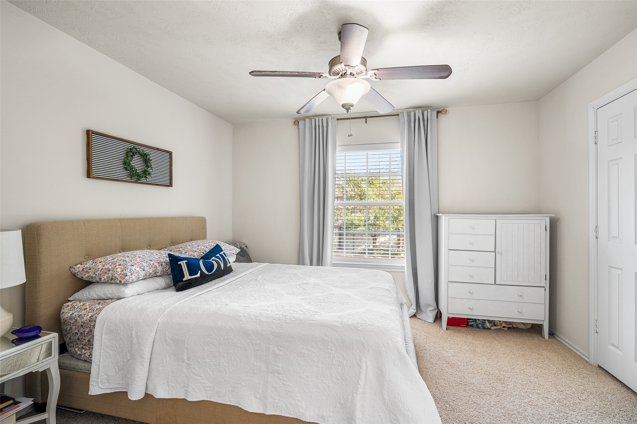 267 Bloomhill Place Magnolia, TX 77354 - Photo 12 of 19 This bedroom showcases plush carpeting, a ceiling fan, and a large window with privacy blinds, providing a bright and comfortable living space.