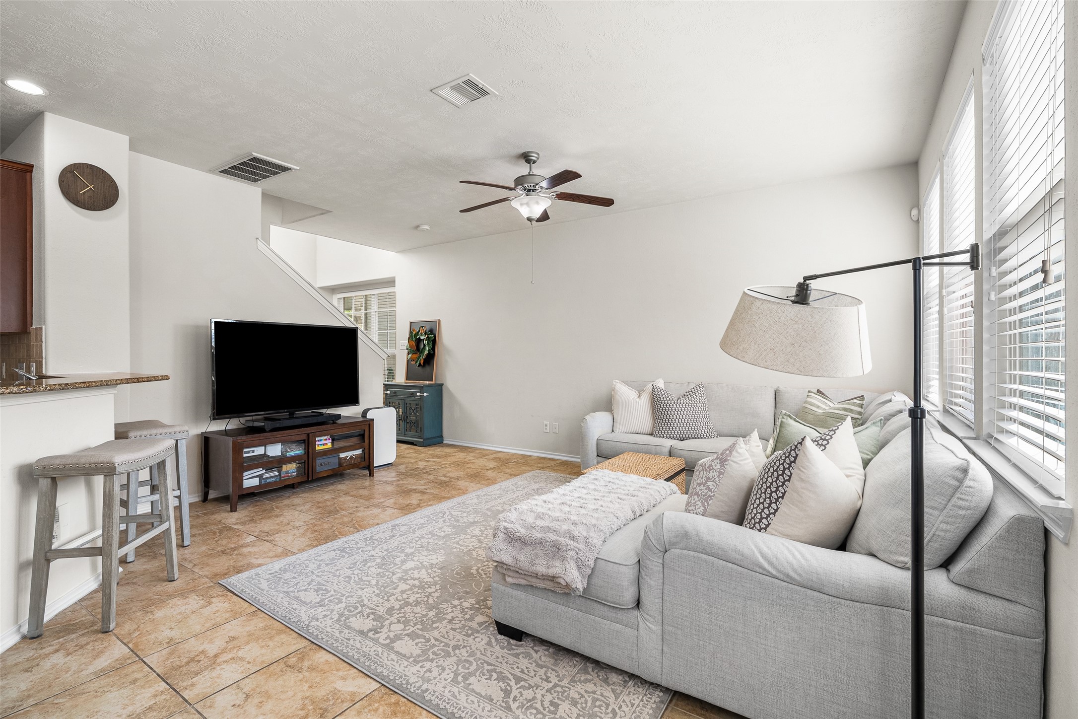267 Bloomhill Place Magnolia, TX 77354 - Photo 3 of 19 The living room features a dark stained ceiling fan, windows with privacy blinds, and tile flooring, offering a bright, modern, and sophisticated space designed for both comfort and style.