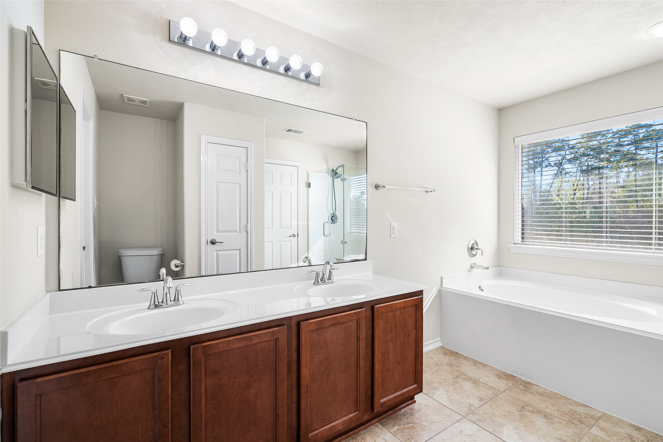 267 Bloomhill Place Magnolia, TX 77354 - Photo 9 of 19 The primary bathroom also features a double sink vanity, an over-sized mirror, and stylish toilet, combining functionality with modern elegance.