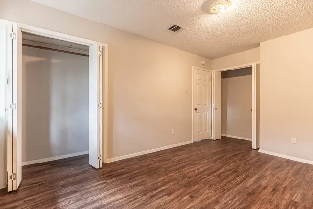 a view of an empty room with wooden floor and closet