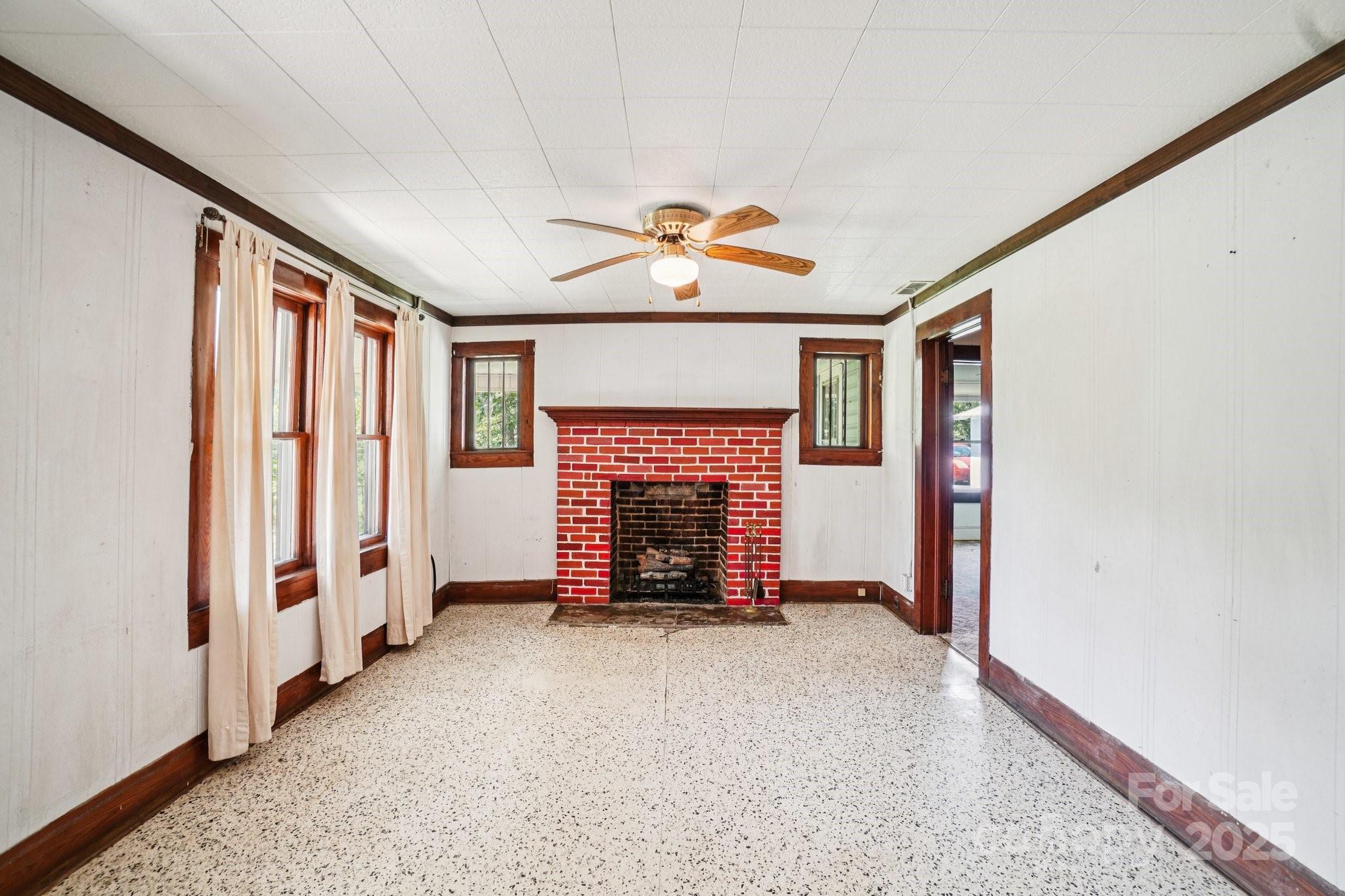 203 North Beaverdam Road Candler, NC 28715 - Photo 11 of 40 an empty room with windows chandelier fan and a fireplace