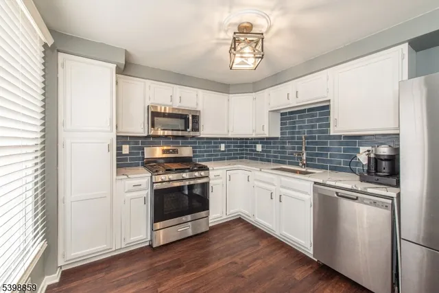 a kitchen with cabinets stainless steel appliances a sink and wooden floor