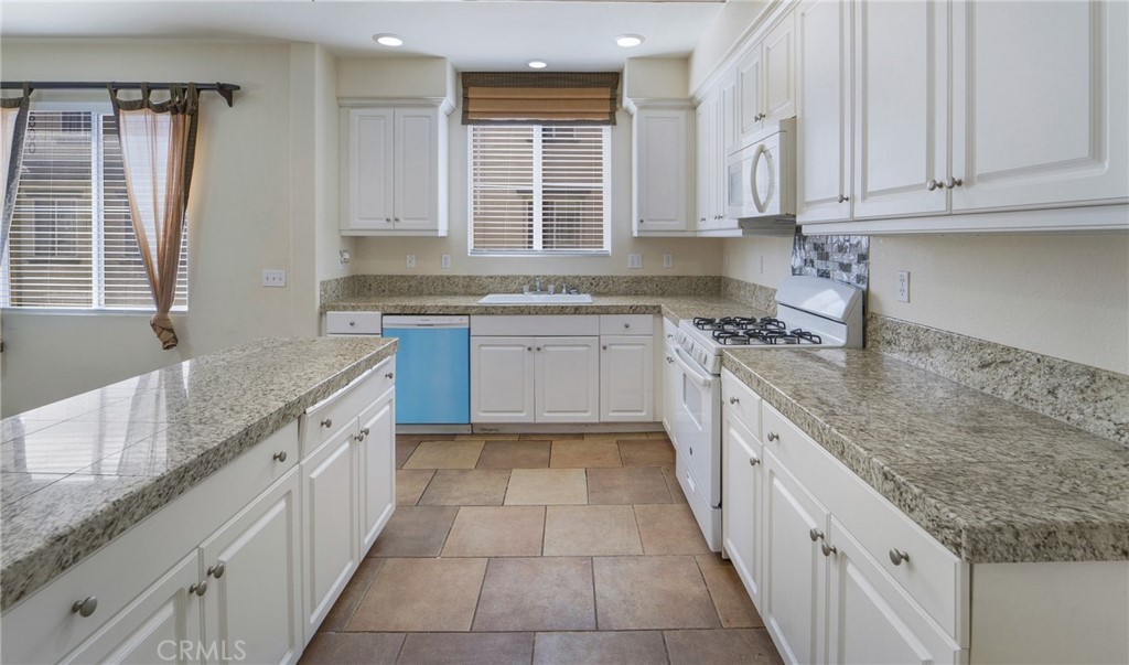 a large kitchen with granite countertop a sink stove and cabinets