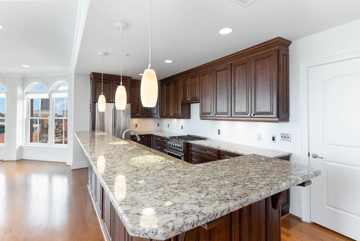710 Independence Place, Unit 606 Raleigh, NC 27603 - Photo 5 of 21 a kitchen with kitchen island granite countertop wooden cabinets a sink and dishwasher