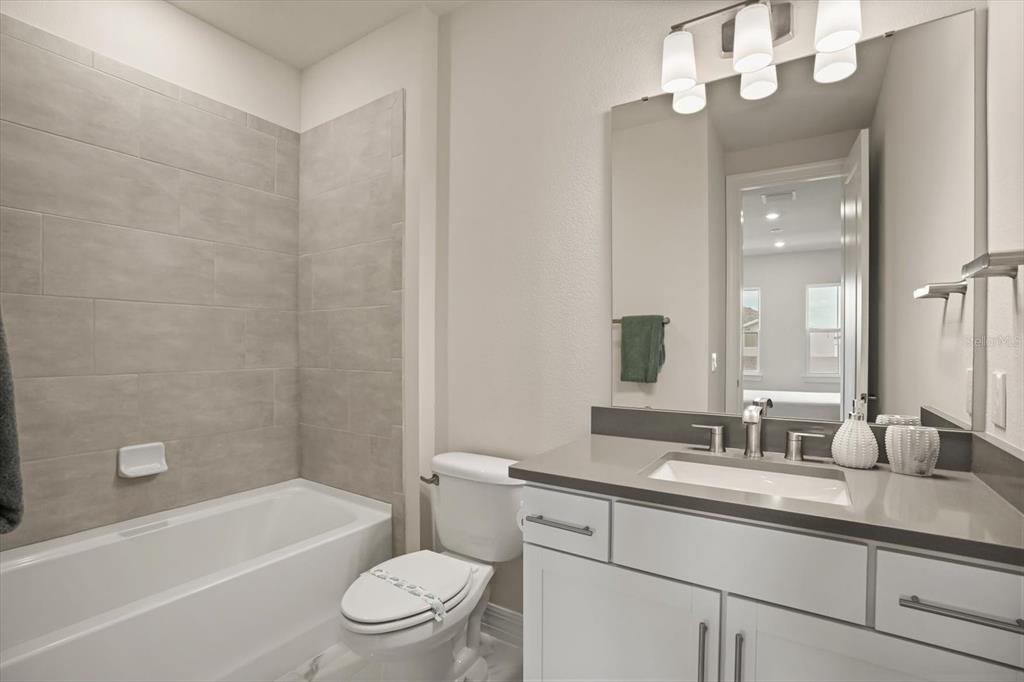 8352 Pk Clf Way Orlando, FL 32836 - Photo 50 of 55 a bathroom with a granite countertop sink a toilet a mirror a bathtub and shower