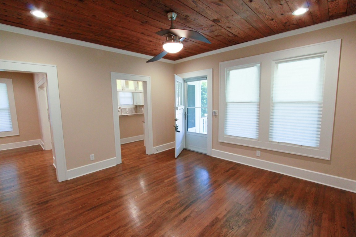 a view of an empty room with wooden floor and a window