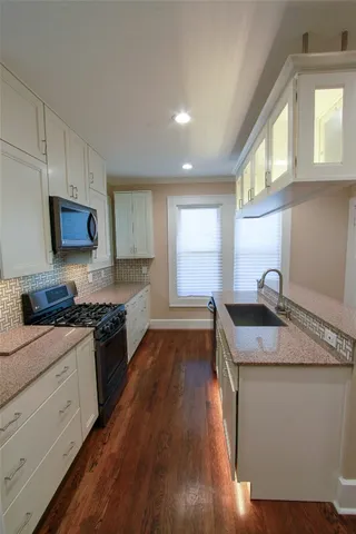 a kitchen with granite countertop a sink stove and cabinets